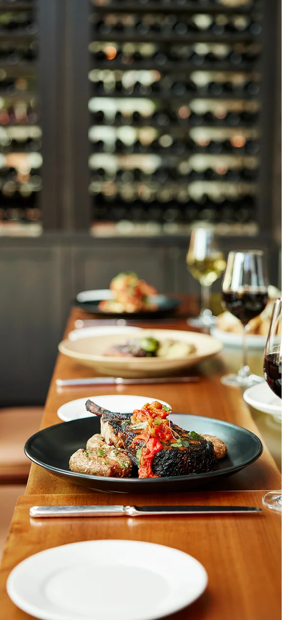 Table with plates and food and glasses of wine on it