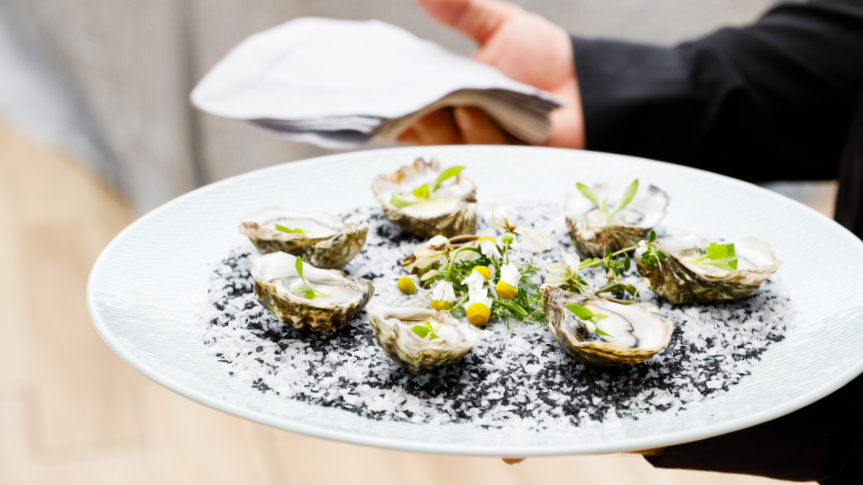 A server holding a plate of oyesters