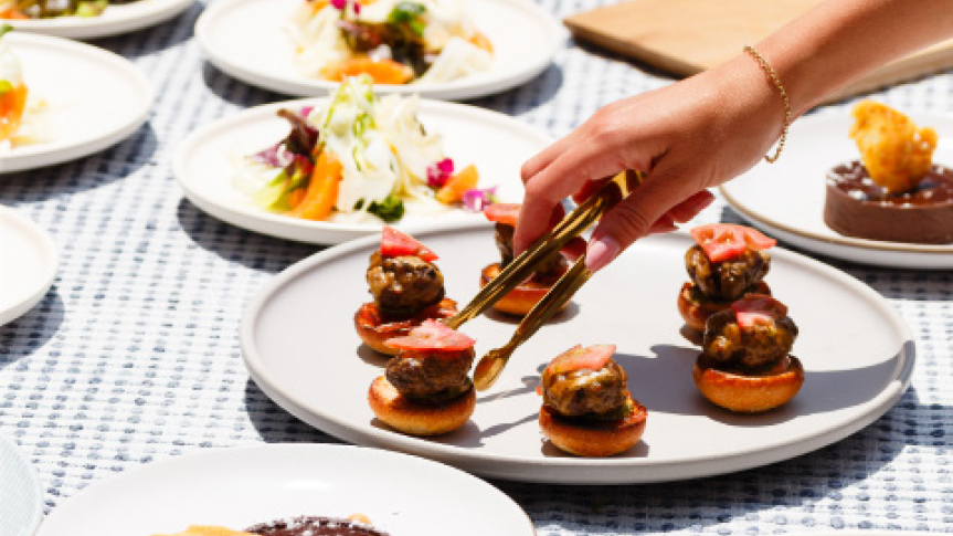 a person holding tongs over food on plates