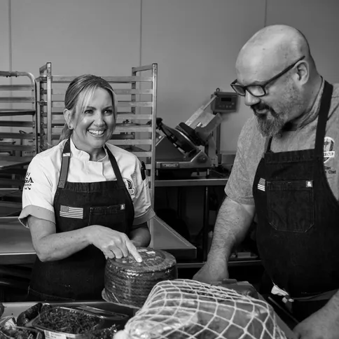 a man and woman in aprons smiling in a kitchen