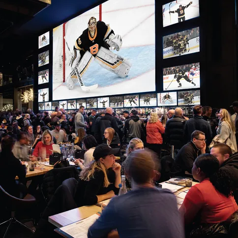 A large group of people sitting at tables with large screens