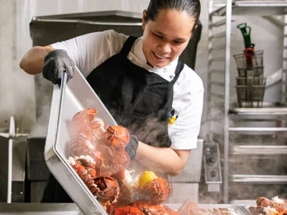 Chef preparing fresh lobsters in kitchen.