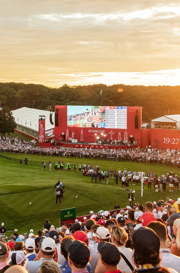 Crowd watching golf event at sunset