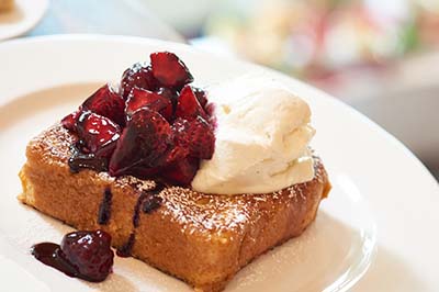 French toast covered with berries, whipped cream and powdered sugar