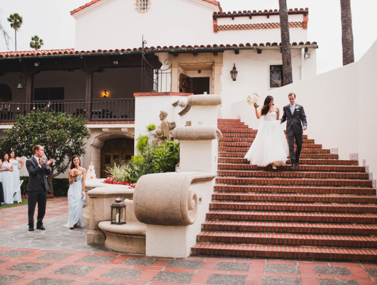 Newlyweds walking down grand brick staircase to the outdoor reception area