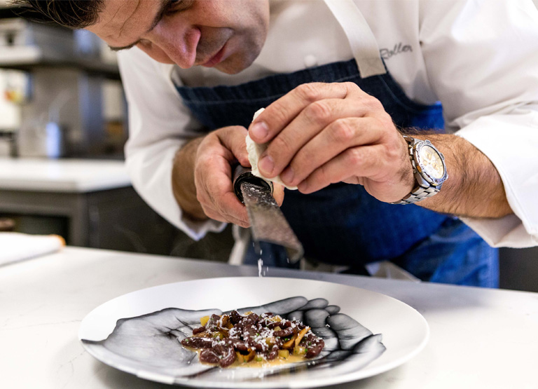 Chef grates cheese over a dish served at Patina Restaurant in Los Angeles